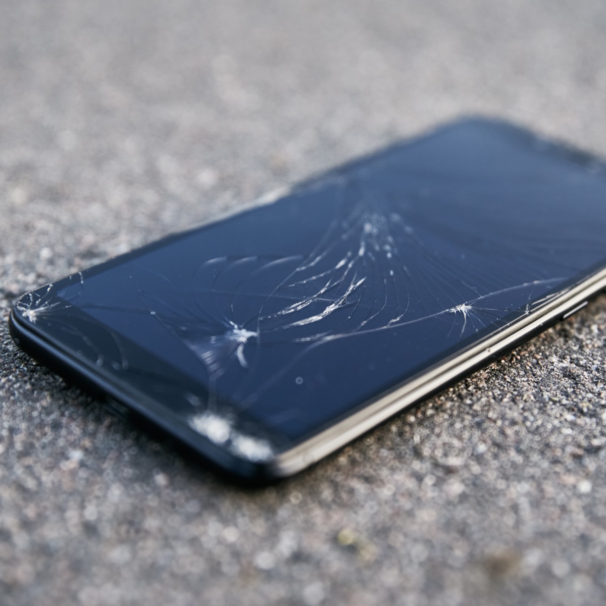 cell phone with cracked screen laying on ground